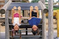 children hanging upside down from claimbing frame