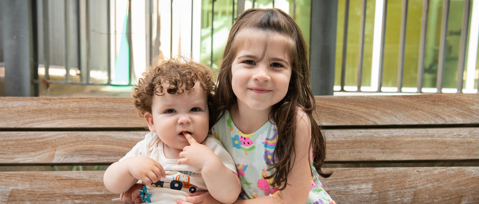 Two siblings hugging on a bench