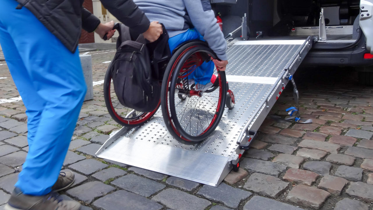 A person in a wheelchair being helping into the back of a bus