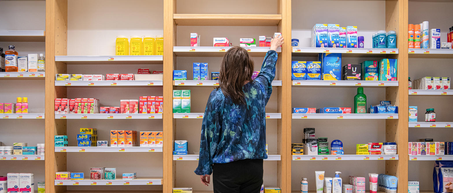 A customer in a pharmacy selecting a product from a shelf