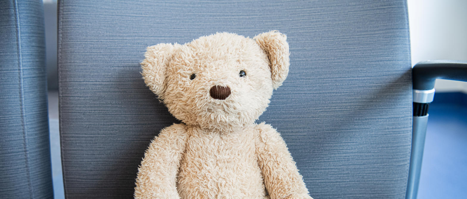 A teddy bear sitting on a waiting area chair