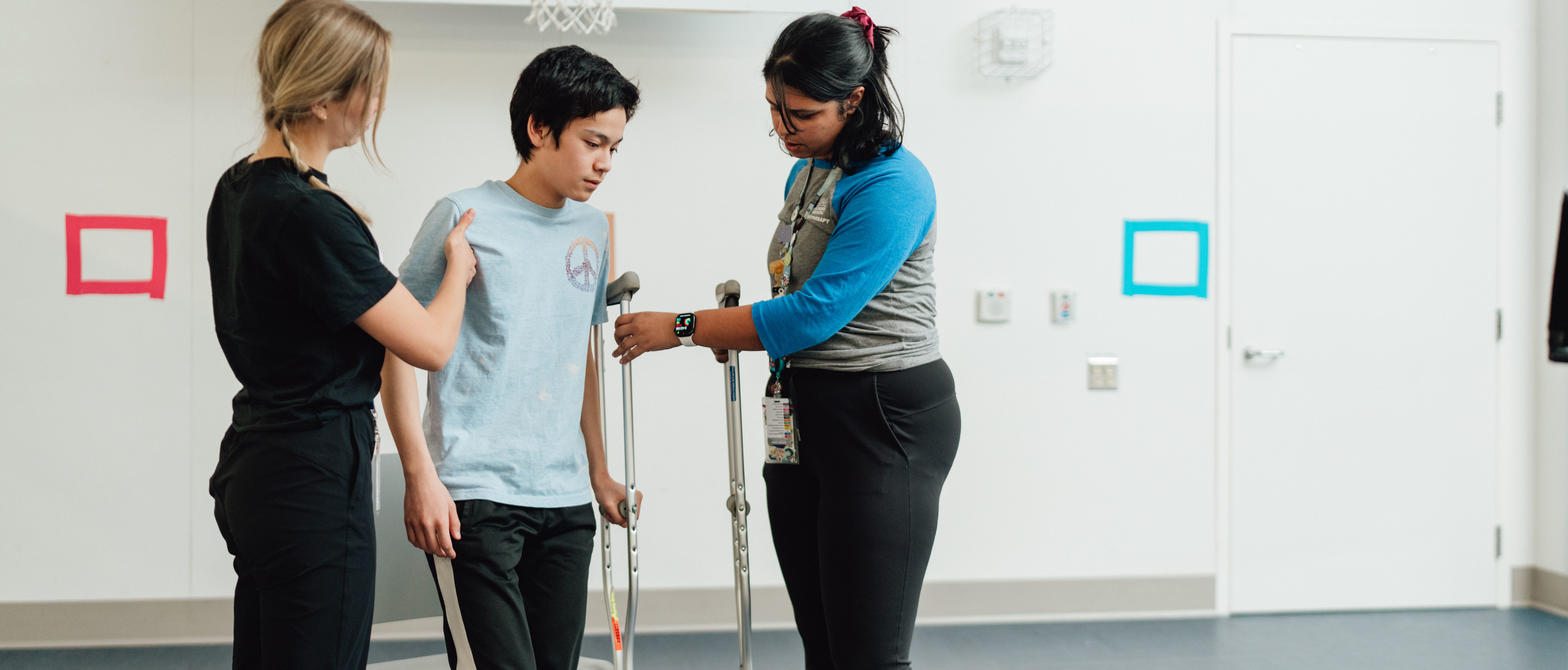 Physiotherapists helping child with crutches walk