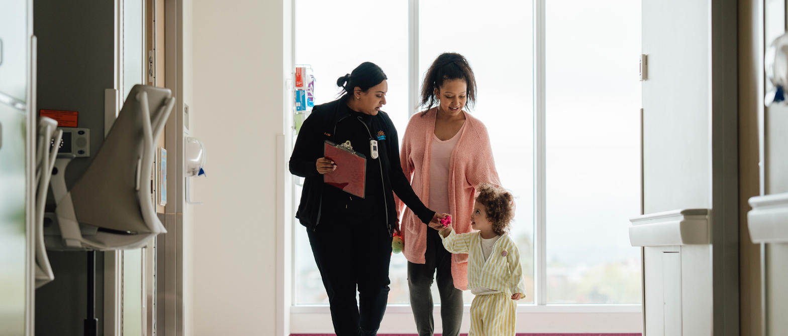 A nurse walking with a child and parent