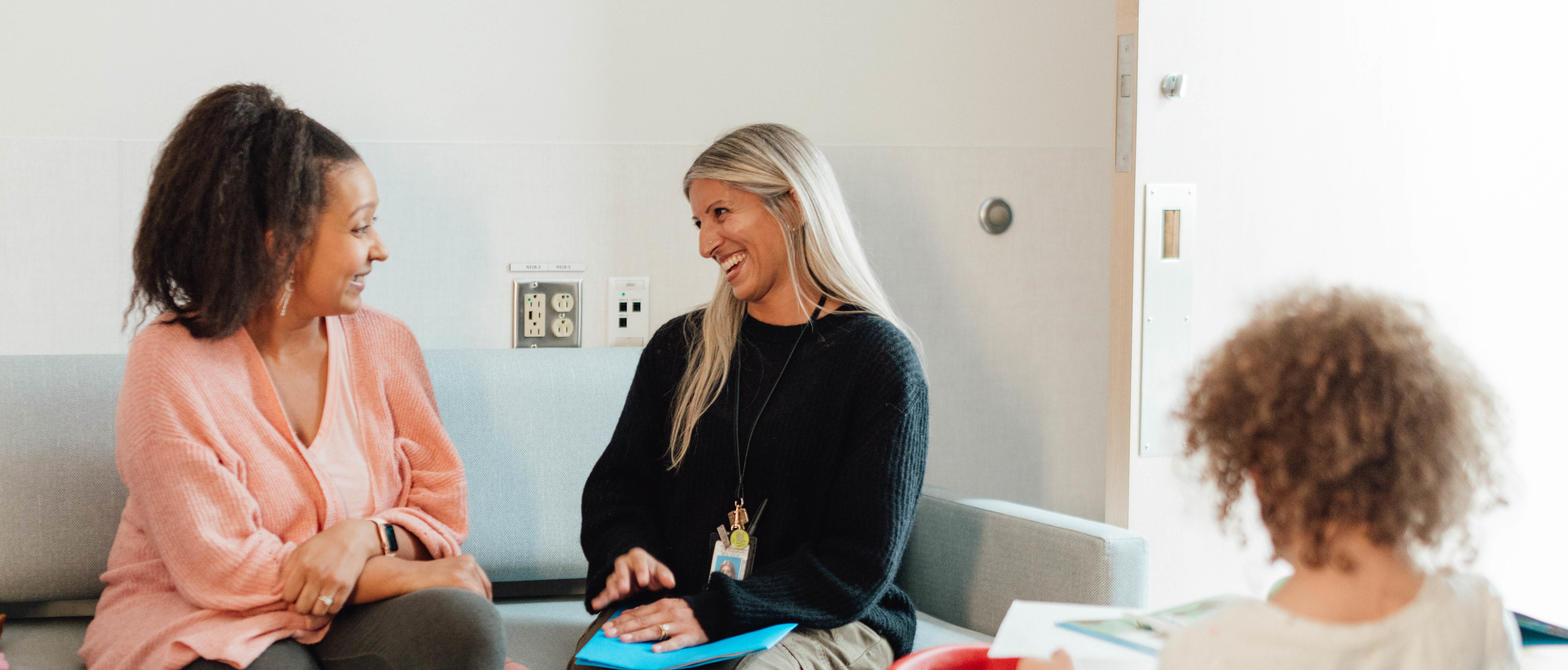Physician sitting with patient family smiling while child plays