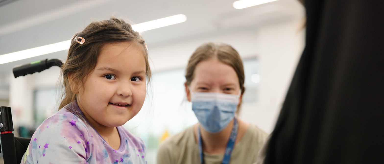 A child smiling at the camera while visiting with a therapy rabbit