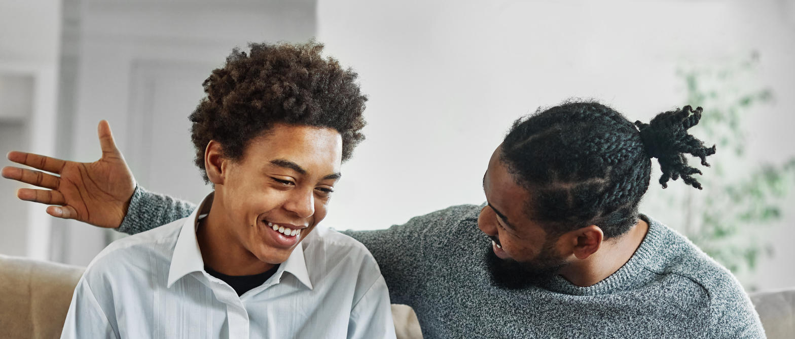 Father and son talking while sitting on couch