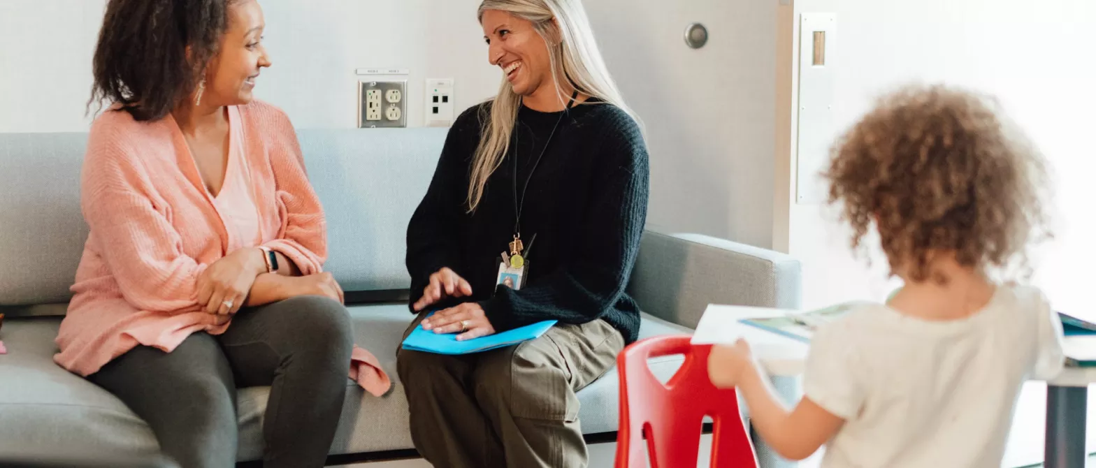 Physician sitting with patient family smiling while child plays