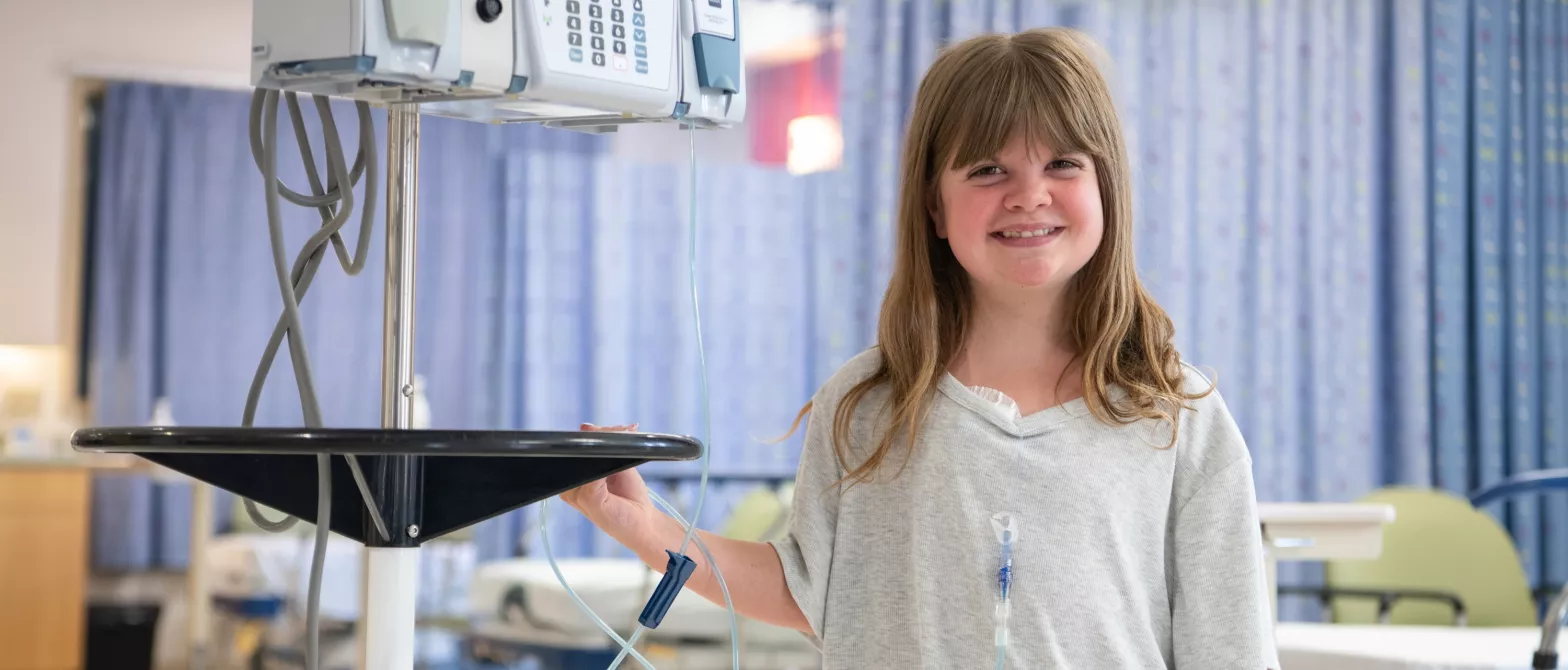 A child smiling next to an IV machine