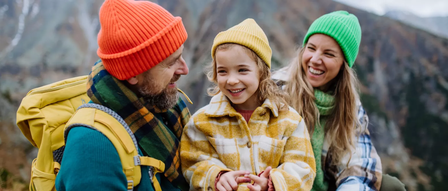 A family laughs while stopping at the summit of a mountain