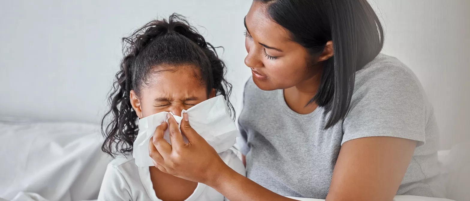 Mother helping child blow nose