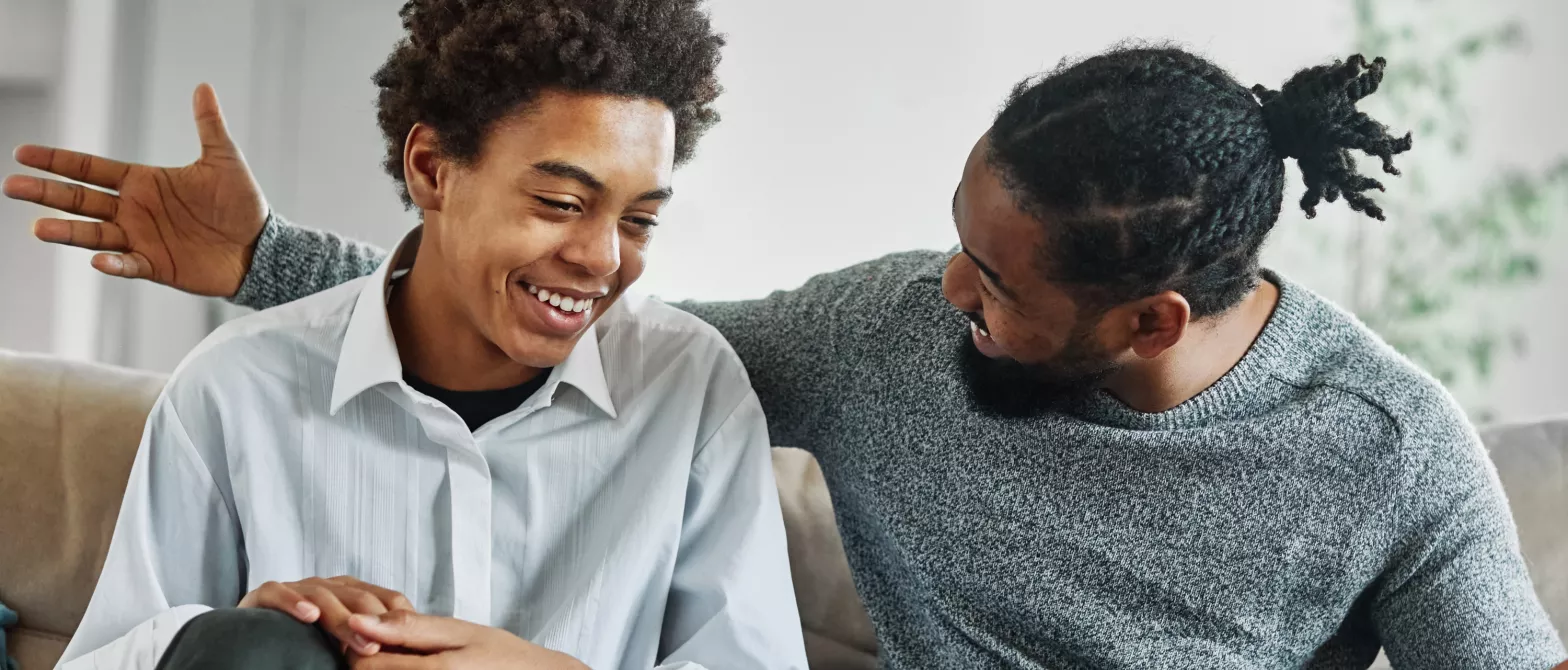 Father and son talking while sitting on couch