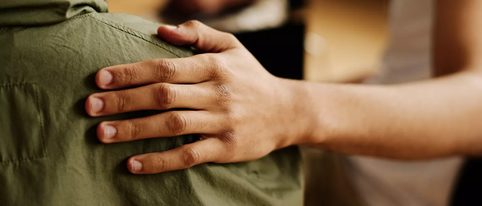 A person giving comfort to someone by placing their hand on their back