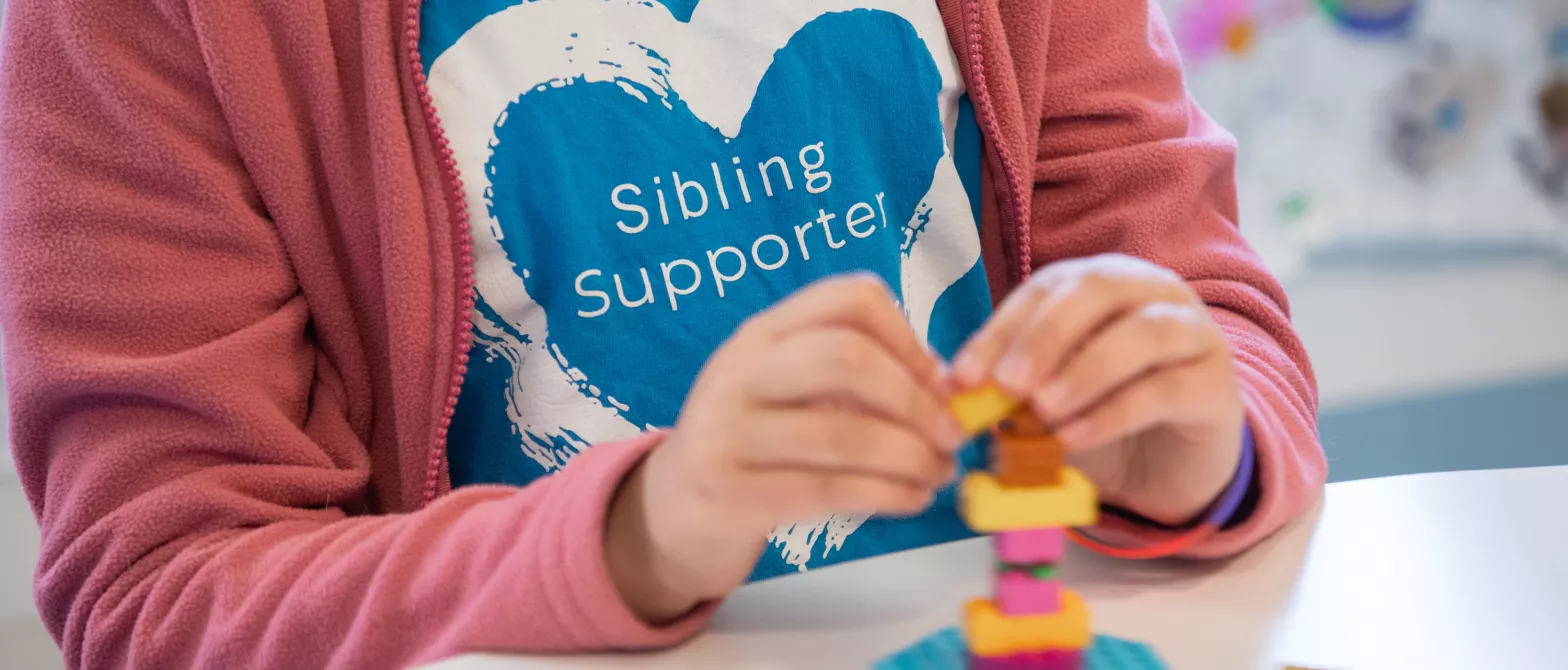 Child wearing shirt that reads Sibling Supporter