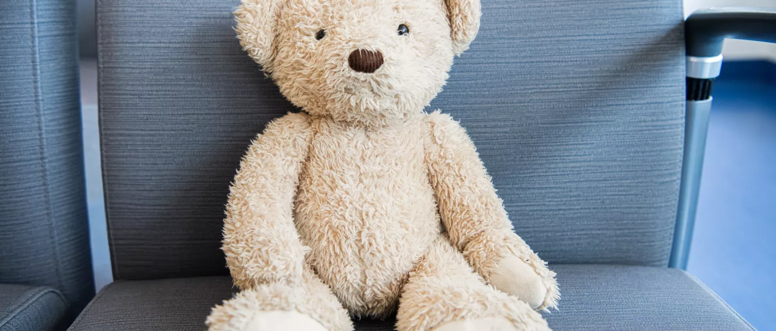A teddy bear sitting on a waiting area chair