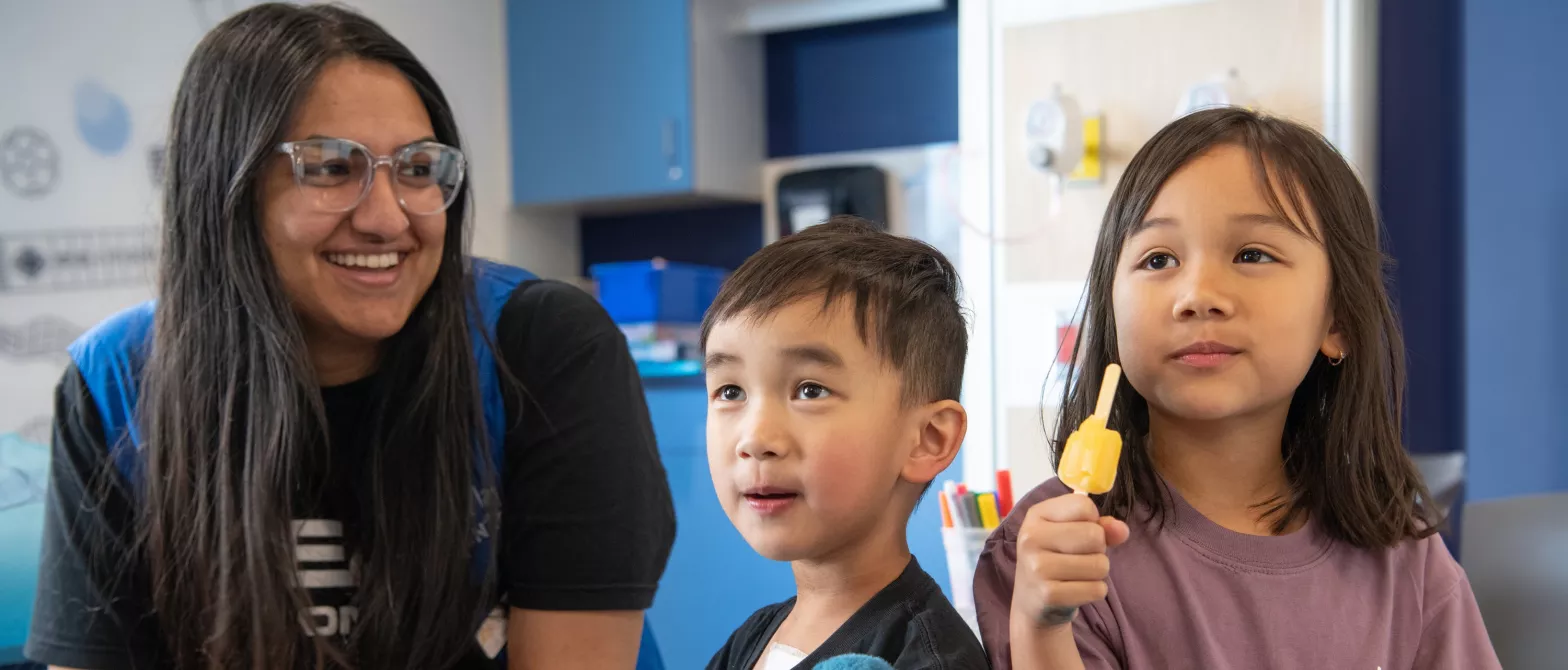 two siblings with volunteer eating popsicle