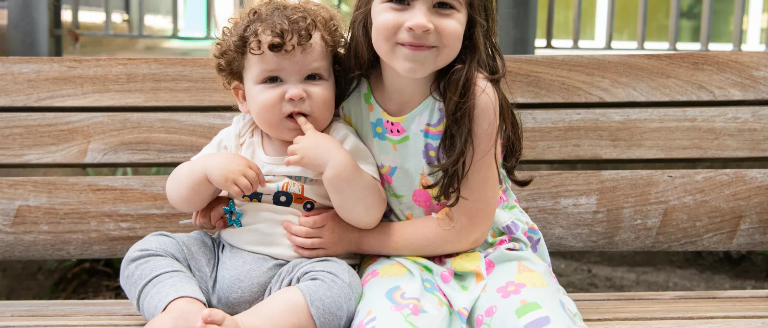 Two siblings hugging on a bench