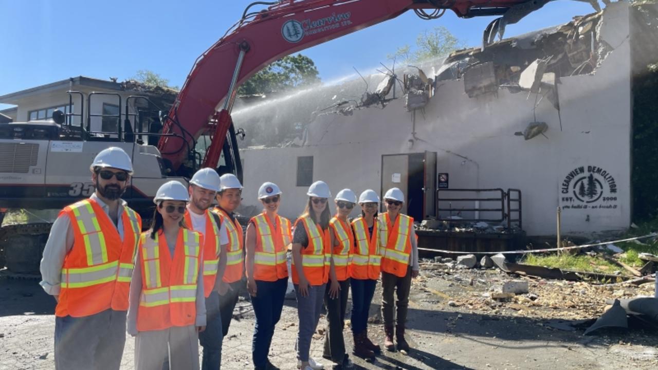 Slocan Site Redevelopment Project team posing in front of an excavator beginning the demolition