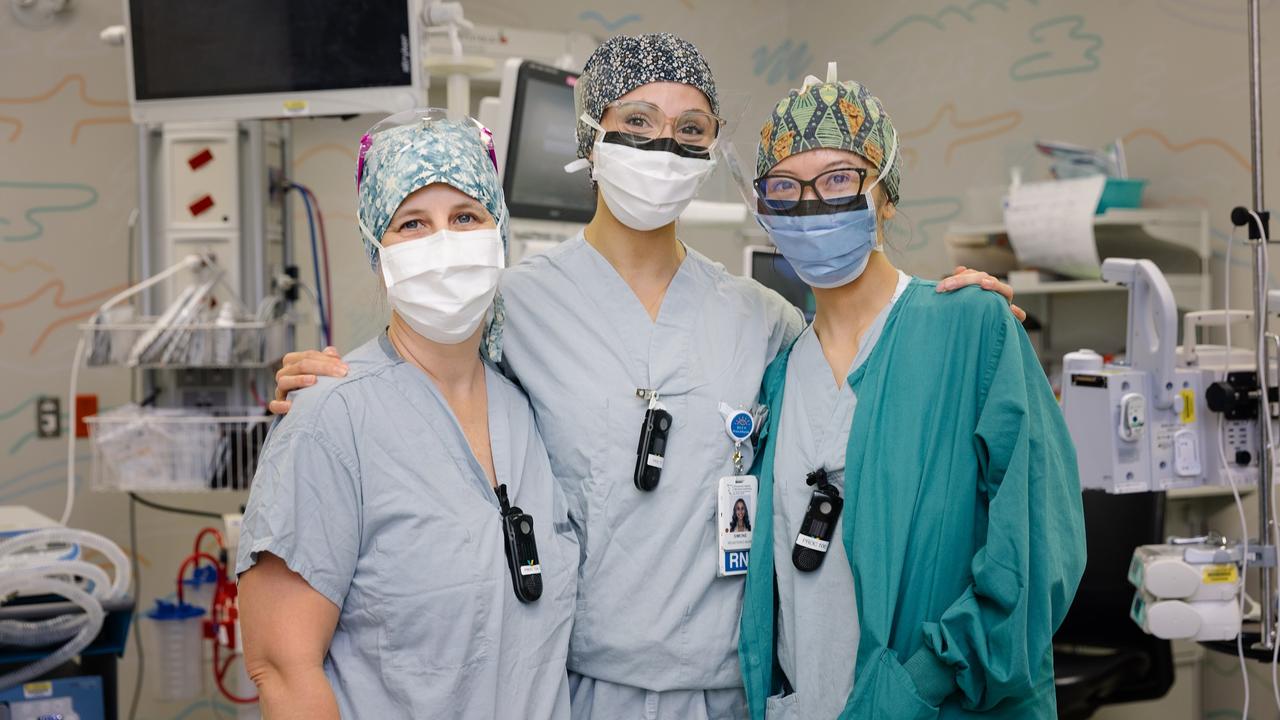 Three staff members in surgical gowns and masks
