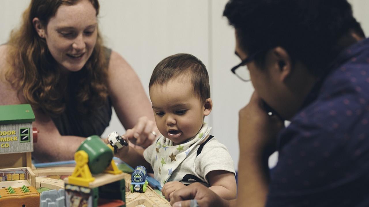 Toddler and two adults playing with toys