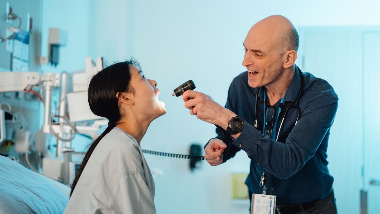 Physician looking into patient's throat with light