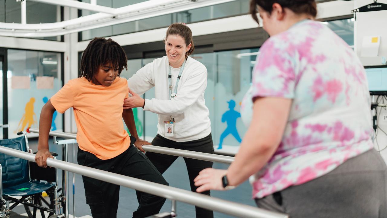 Physiotherapists working with a child on walking pad