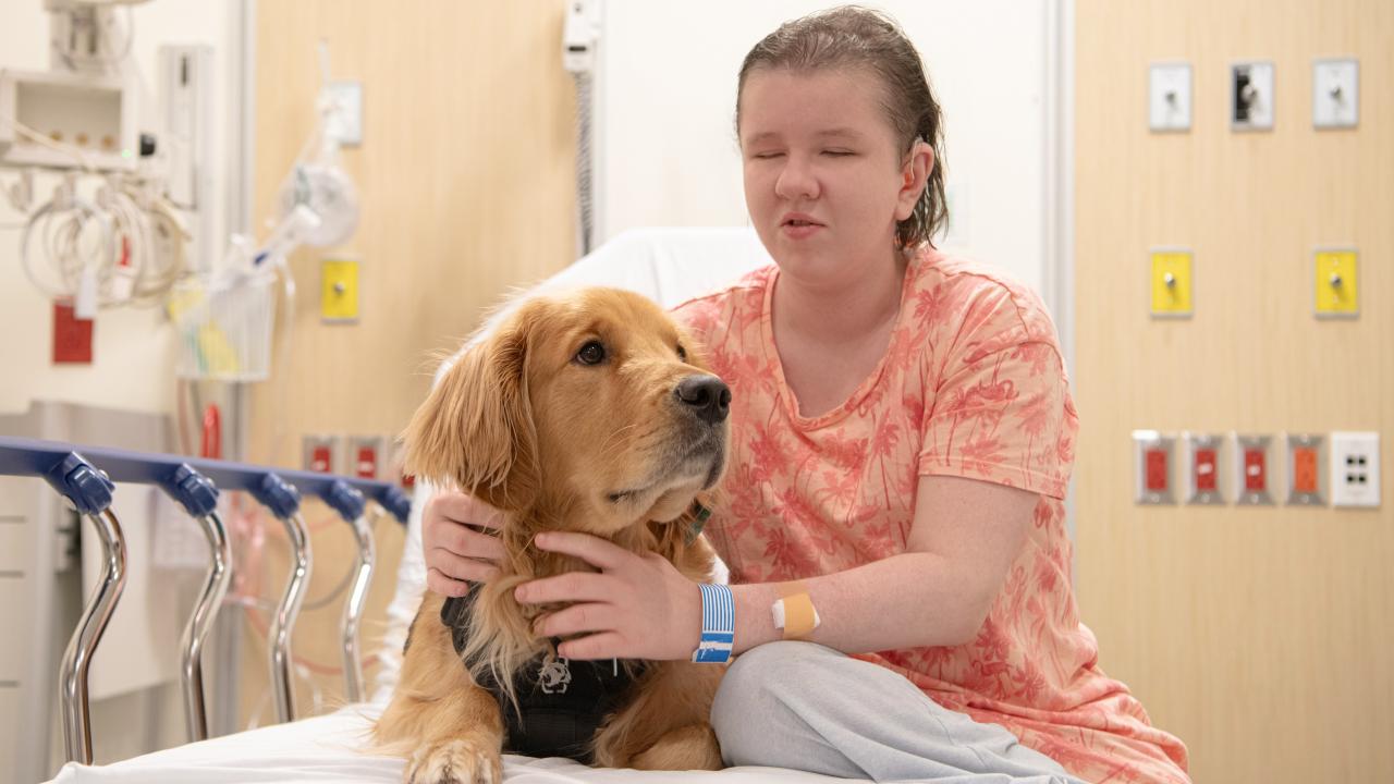 A patient hugging a dog on a bed in BC Children's Hospital