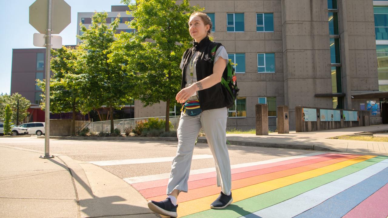 A hospital employee walking across a rainbow crosswalk