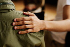 A person giving comfort to someone by placing their hand on their back