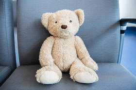 A teddy bear sitting on a waiting area chair