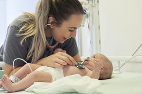 Nurse with infant patient listening to heart