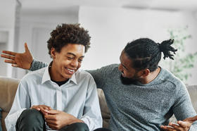 Father and son talking while sitting on couch