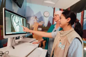 Two medical imaging technologists reviewing an image on a computer screen