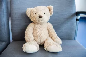 A teddy bear sitting on a waiting area chair