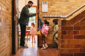 Teacher high-fives children as they enter classroom