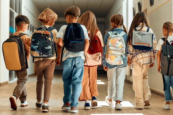 Children with backpacks walking in the hallway at school