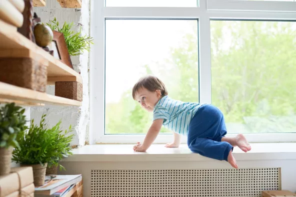 Young child crawling by a window, highlighting the risk of falls from windows