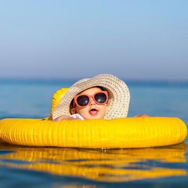 Baby in sunhat and sunglasses swimming with floatie