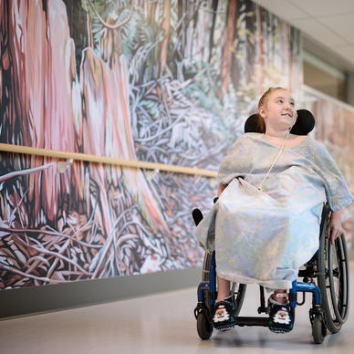 Child wheeling down hospital corridor in a wheelchair