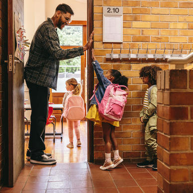 Teacher high-fives children as they enter classroom