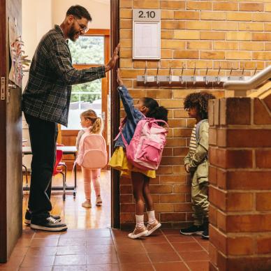 Teacher high-fives children as they enter classroom
